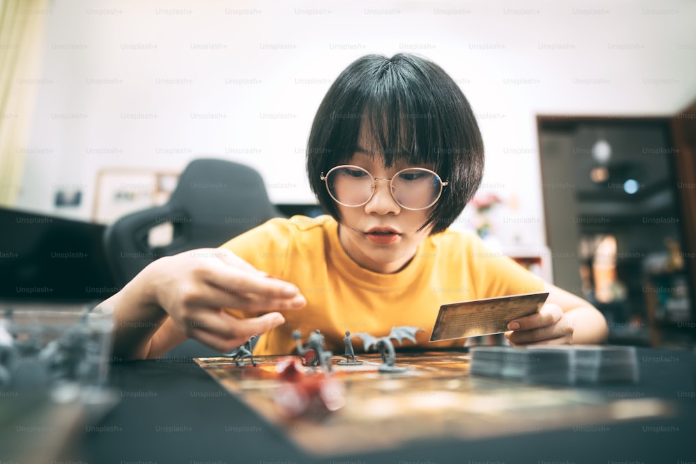 Gli hobby delle persone, lo stile di vita, rimangono a casa, il concetto. Giovane donna asiatica adulta che gioca al gioco da tavolo sul tavolo superiore.