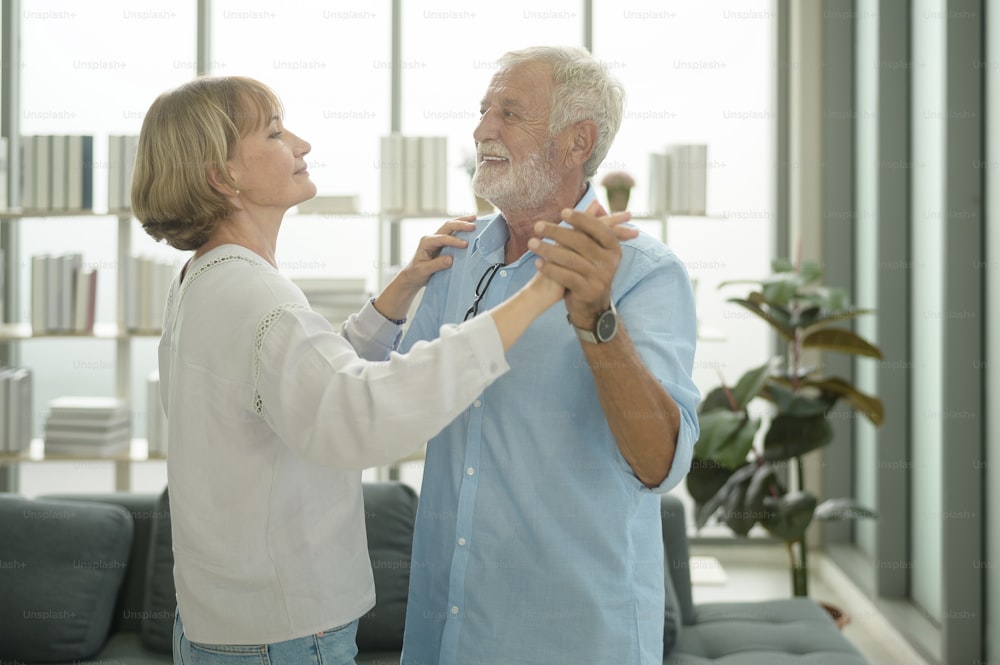 Happy Caucasian senior couple dancing at home