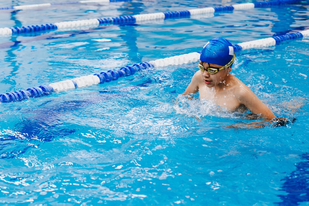 latin child boy swimmer wearing cap and goggles in a swimming training at the Pool in Mexico Latin America