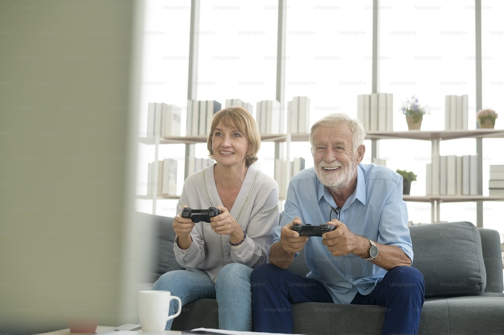 家でゲームをしている幸せな白人の老夫婦