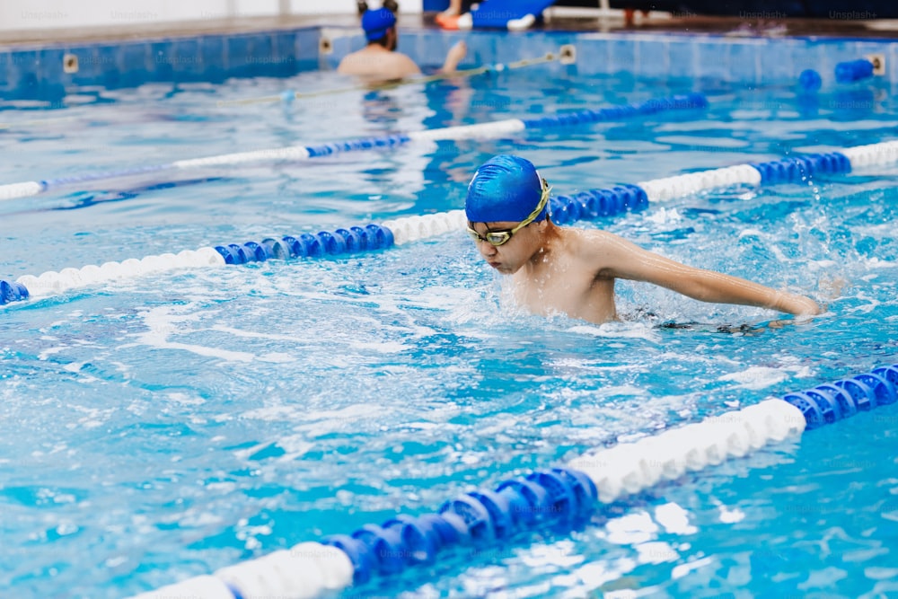 latin child boy swimmer wearing cap and goggles in a swimming training at the Pool in Mexico Latin America