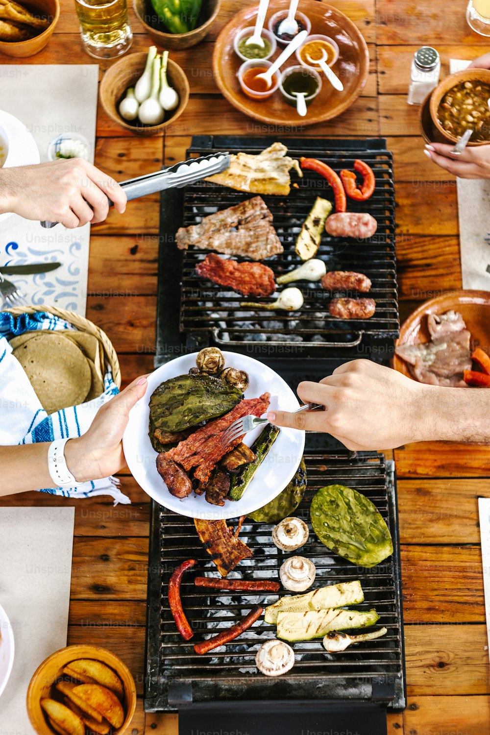 group of latin Friends eating Mexican Tacos and traditional food, snacks and peoples hands over table, top view. Mexican cuisine Latin America