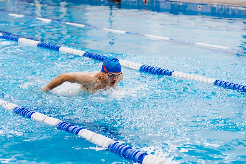 히스패닉 청년 수영 선수는 멕시코 라틴 아메리카의 수영장에서 수영 훈련에서 모자를 쓰고 있습니다.