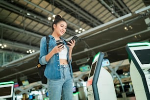 young asian female traveller checking online register checkin and map location for new trip abroad with smiling and pleasure,travel after covid lockdown is over happiness femal walk in airport hub