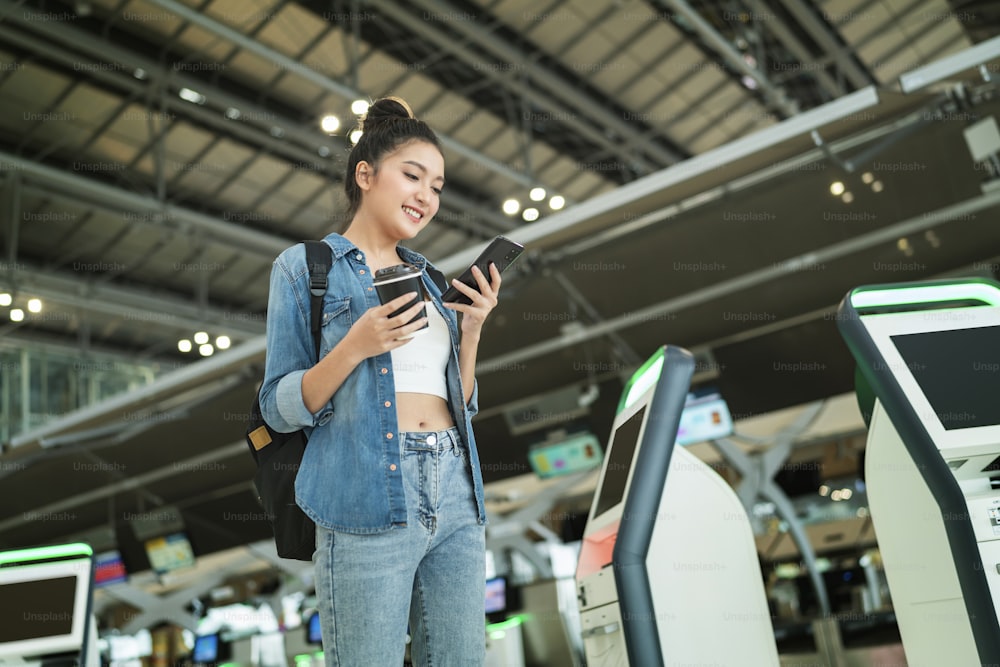 young asian female traveller checking online register checkin and map location for new trip abroad with smiling and pleasure,travel after covid lockdown is over happiness femal walk in airport hub