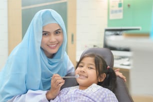 A little cute girl having teeth examined by muslim dentist in dental clinic, teeth check-up and Healthy teeth concept