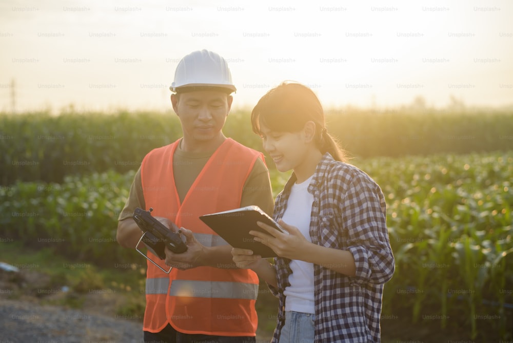 Un ingegnere maschio fornisce una consulenza e istruzioni per l'agricoltore intelligente con droni che spruzzano fertilizzanti e pesticidi su terreni agricoli, innovazioni ad alta tecnologia e agricoltura intelligente