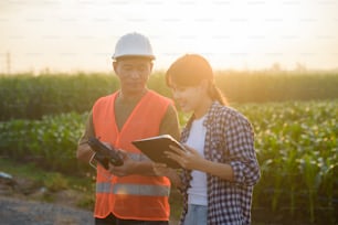Un ingeniero masculino brinda una consulta e instrucción al agricultor inteligente con drones que rocían fertilizantes y pesticidas sobre tierras de cultivo, innovaciones de alta tecnología y agricultura inteligente