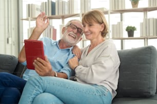 Caucasian happy seniors elderly are video calling to family or friends, relax at home, smiling healthy senior retired grandparents, older grandparent technology concept