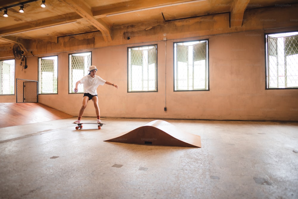 skater woman person playing skateboard in sport gym, young Asian woman are happy and fun with skateboarding lifestyle in city, teenage hipster female trendy fashion