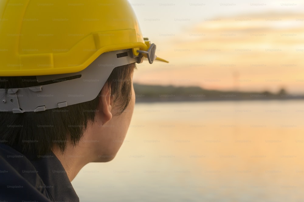 Um engenheiro do sexo masculino usando um capacete de proteção ao pôr do sol.