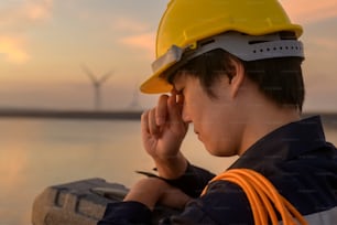 A male engineer wearing a protective helmet at sunset.
