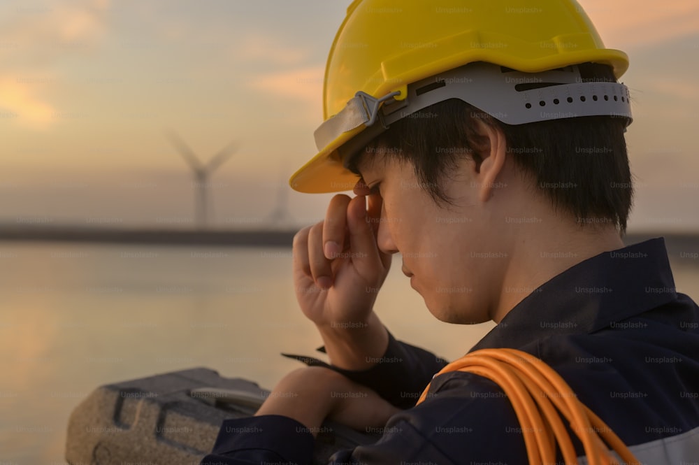A male engineer wearing a protective helmet at sunset.
