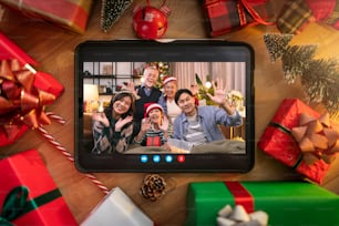 Relation de distance de salutation familiale Tablet Device entre Noël Decoration.tablet avec une famille asiatique dire bonjour fond. Cadre de Noël pour carte de voeux. Vue d’en haut avec espace de copie