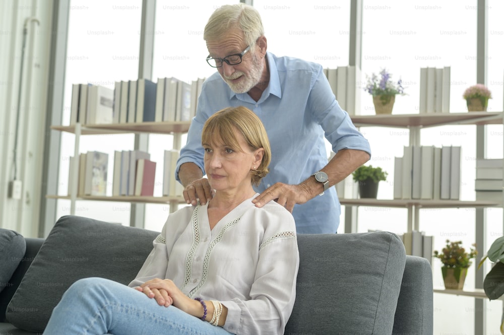 Senior caucasian man doing massage for his wife in living room