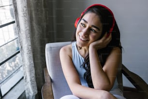 ヘッドフォンを持つ若いラテン系女性、メキシコラテンアメリカの自宅で音楽を聴く