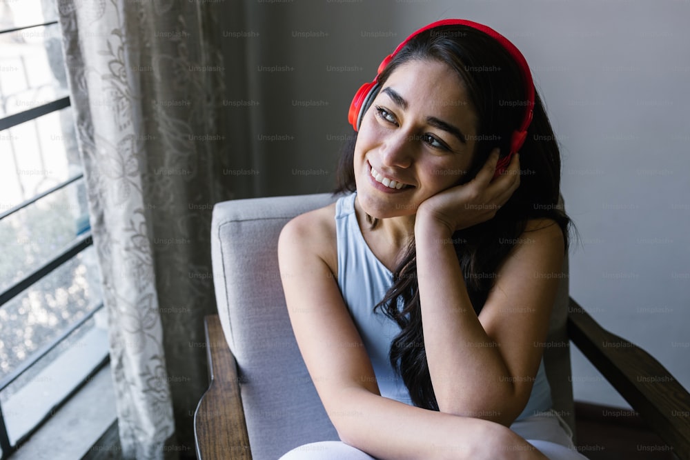 young latin woman with headphones, listening music at home in Mexico Latin America