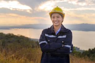 Une ingénieure met un casque de protection sur sa tête au coucher du soleil.