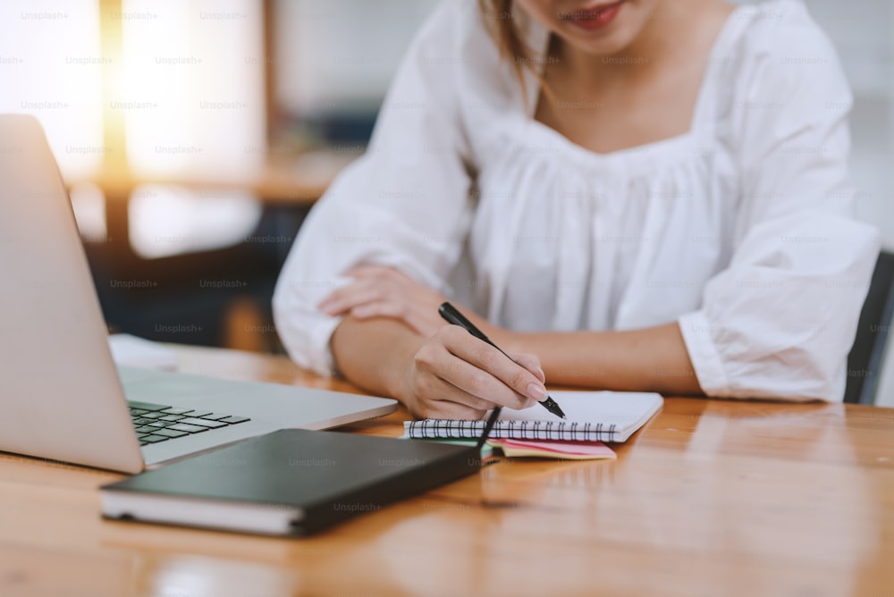 Close up of woman hand using pen taking notes in office.