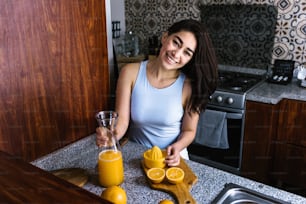 히스패닉 갈색 머리 젊은 라틴 아메리카 멕시코 부엌에서 오렌지 주스를 준비 하는 젊은 라틴 여자