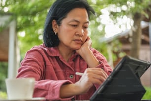 asian woman working with tablet online at coffee shop