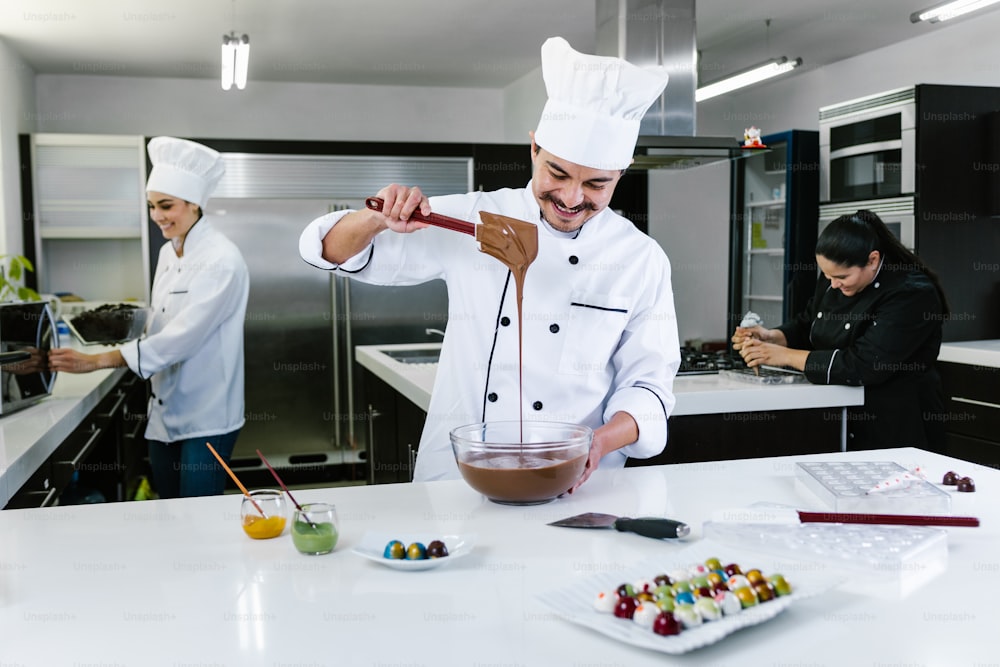 latin man pastry chef wearing uniform in process of preparing delicious sweets chocolates at kitchen in Mexico Latin America