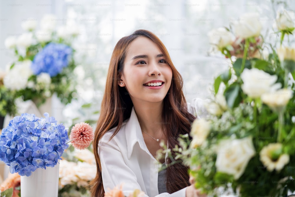 Small business. Asia Female florist smile arranging flowers in floral shop. Flower design store. happiness smiling young lady making flower vase for customers, preparing flower work from home business