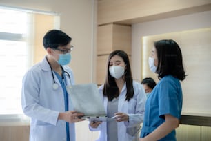 Il medico professionista e il team di medici hanno una conversazione per parlare in ospedale del lavoro di assistenza sanitaria medica, indossando una maschera chirurgica