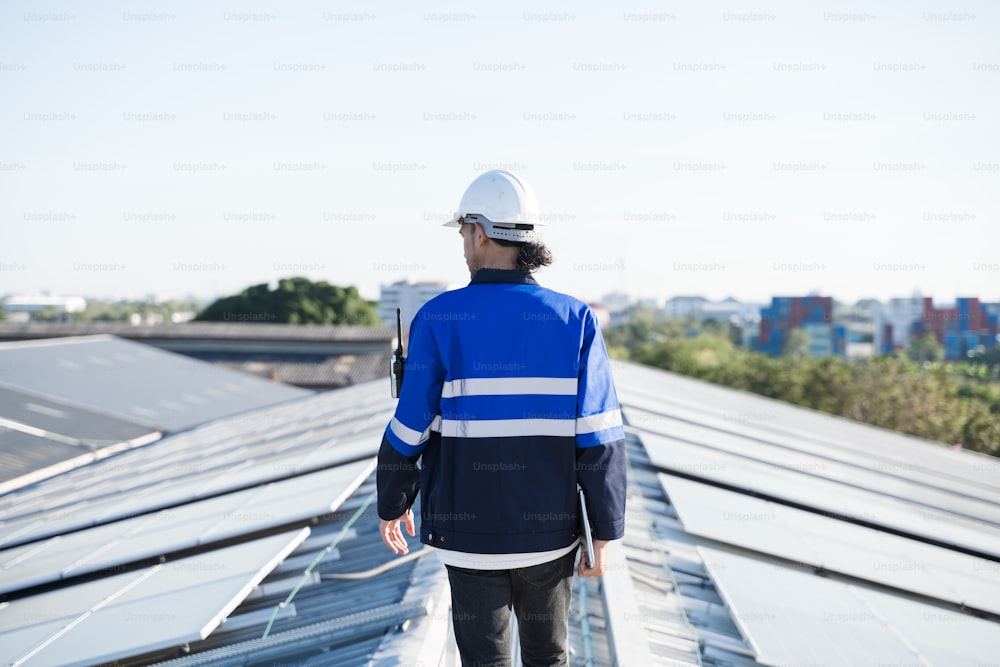Porträt des asiatischen Ingenieurs auf dem Hintergrundfeld der Photovoltaik-Solarmodule Solarzellen auf dem Dach Fabrik.