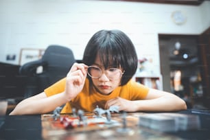 Menschen Lebensstil mit interessantem Hobby zu Hause Konzept. Junge erwachsene asiatische Frau, die Brettspiel am oberen Tisch spielt. Glücklich mit Lächeln Gesicht und Auge in die Kamera schauen.