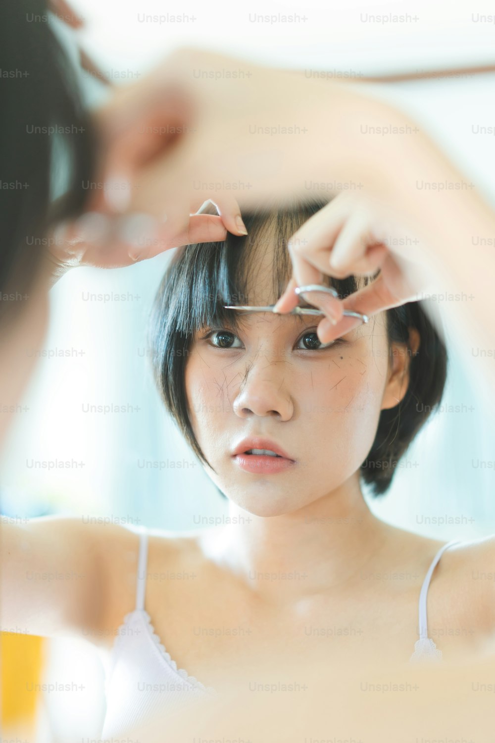 Zufriedenheit Lebensstil Stay at Home Konzept. Junge Erwachsene authentische asiatische Frau selbstschneidend schlägt Haarschnitt mit Schere. Hintergrund am Tag mit Naturlicht.