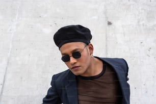 Young latin gay man with make-up on wearing a fashionable hat and sunglasses, isolated on a White background looking at camera. LGBT.