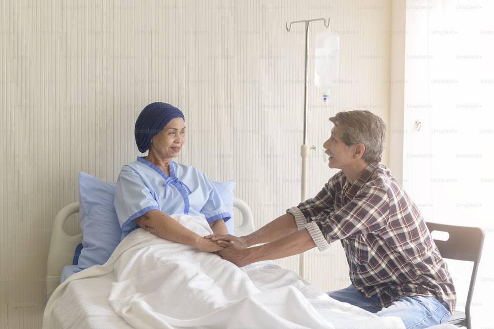 Um homem sênior que visita a mulher paciente com câncer usando lenço na cabeça no hospital, cuidados de saúde e conceito médico