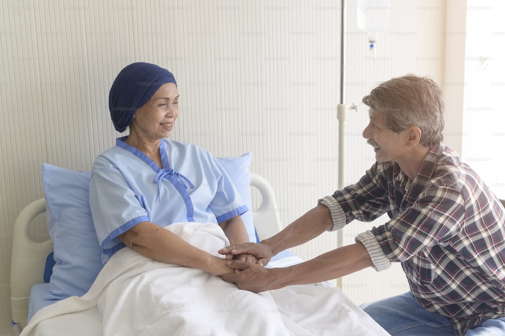 Un hombre mayor que visita a una mujer paciente con cáncer que usa un pañuelo en la cabeza en el hospital, atención médica y concepto médico