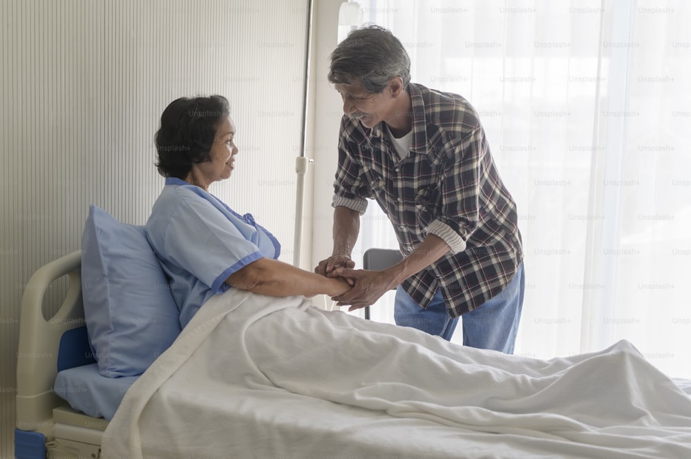 Ein älterer Mann besucht ältere Patientin im Krankenhaus, Gesundheitsversorgung und medizinisches Konzept