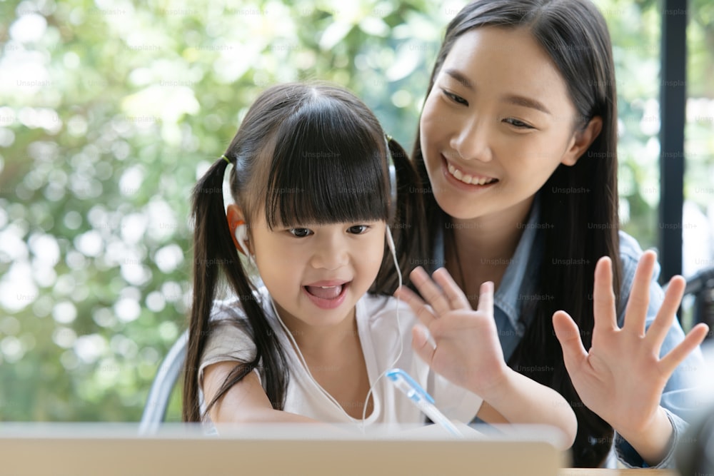 young asian mother teaching her daughter a homework on a laptop. Asian little girl kind enjoy learning with her beautiful mother.