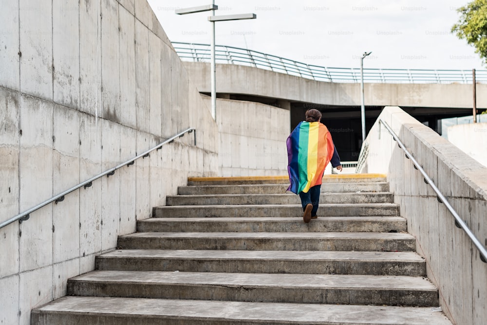 LGBT woman wearing a LGBTQ  rainbow flag on her shoulders, concept of gay pride month, lesbian pride, LGBT awareness movement, non-binary inclusivity, and diversity. Copy space