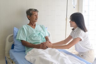 Una hija pequeña que visita a un padre anciano enfermo en el hospital, la atención médica y el concepto médico