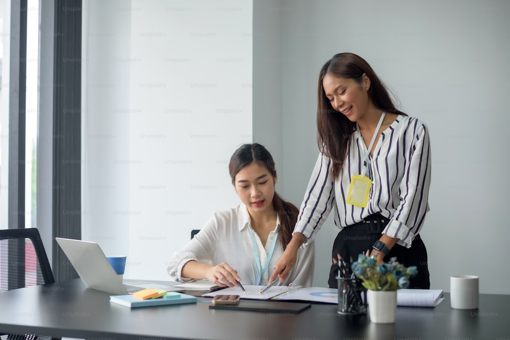 Two beautiful Asian businesswoman talking exchange ideas at work.