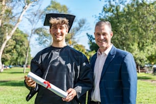 Portrait of a happy caucasian graduated young man with his father on his graduation day.  They are both looking at camera