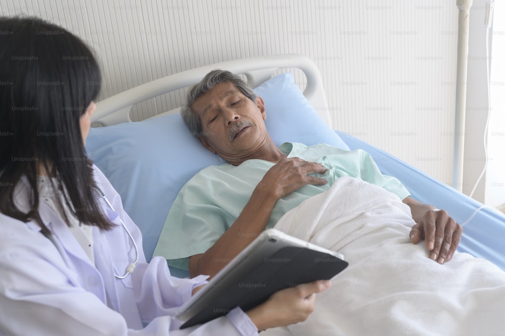 Un paciente masculino asiático de la tercera edad está consultando y visitando al médico en el hospital.