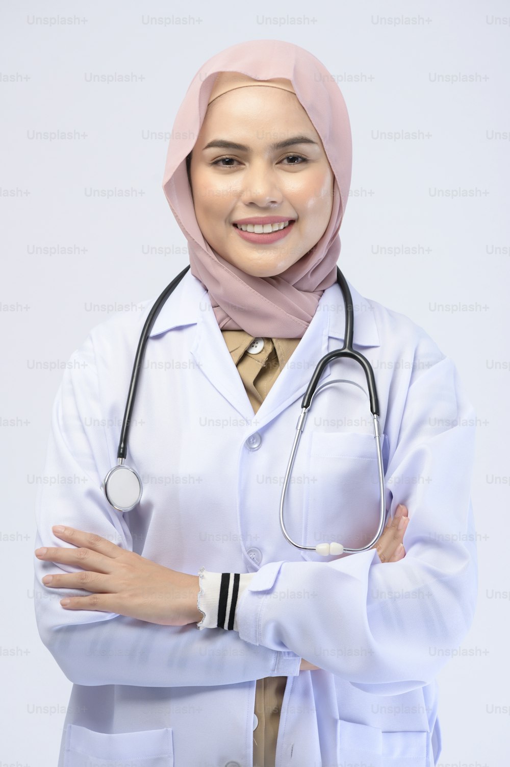 Una doctora musulmana con hiyab sobre fondo blanco estudio.