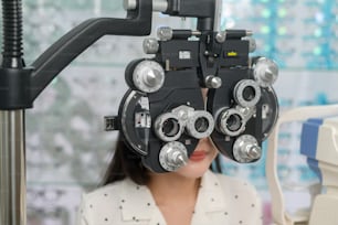Une jeune cliente est examinée par un test visuel à l’aide d’un appareil de mesure de la vue d’optométrie bifocale par un ophtalmologiste dans un centre optique, concept de soins oculaires.