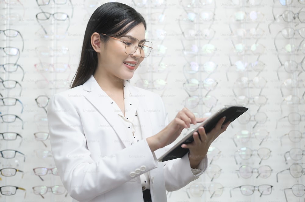 A Young ophthalmologist holding tablet in optical center, eyecare concept.