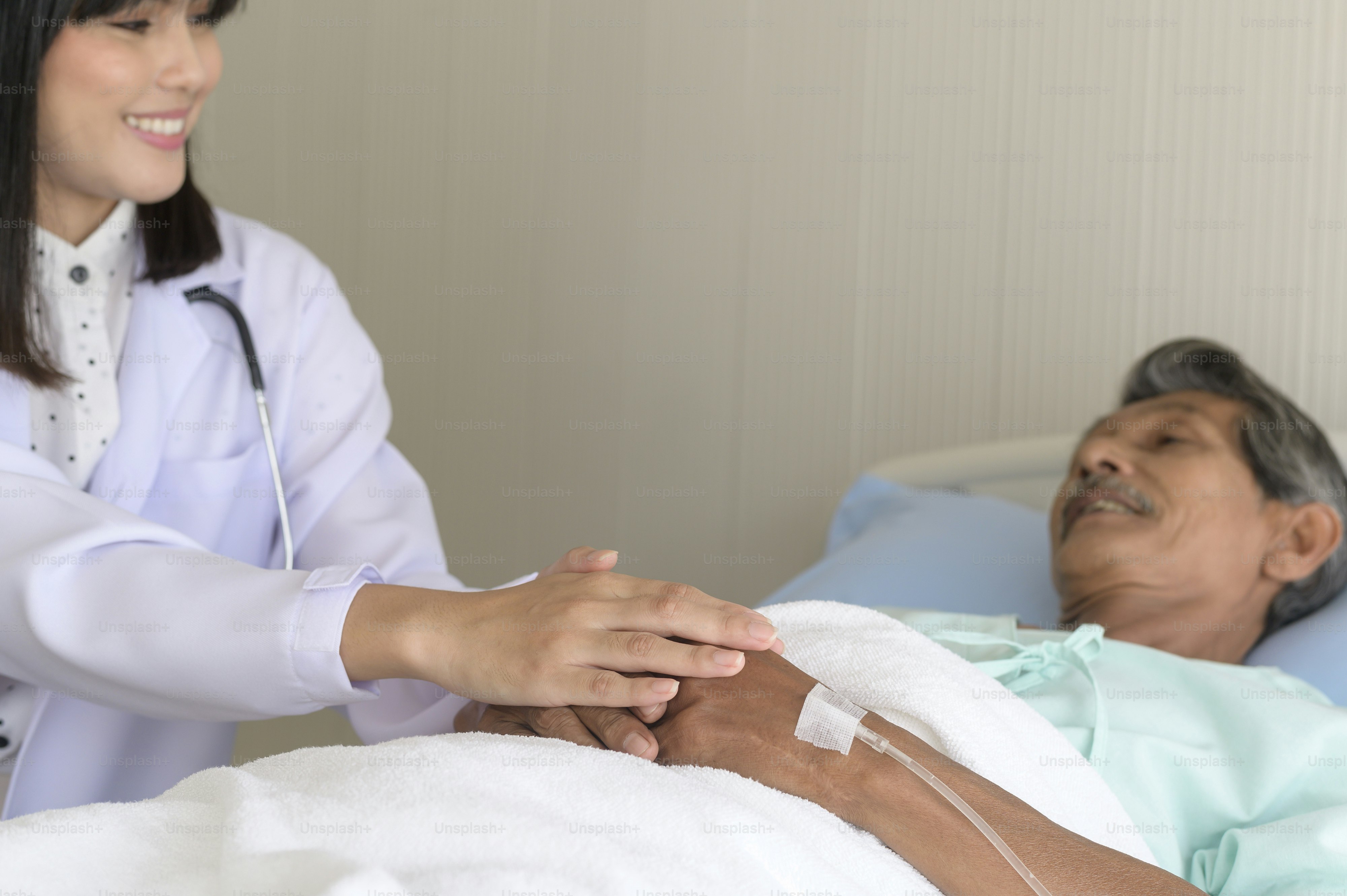 Doctor holding senior patient's hand in hospital, health care and medical concept
