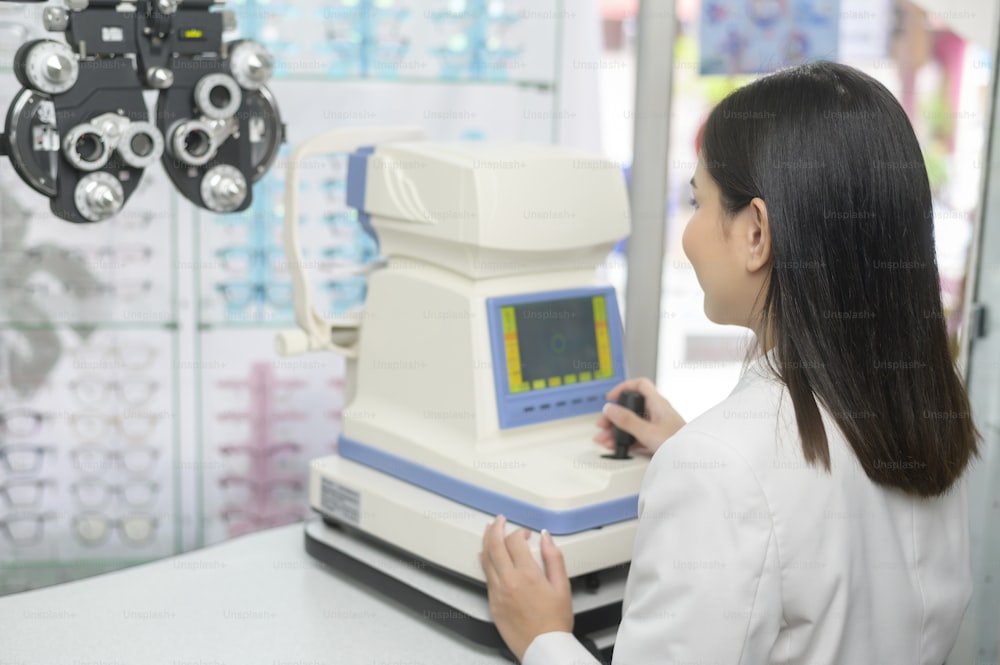 Um jovem oftalmologista fazendo um teste visual para o cliente usando auto-refrator em centro óptico, conceito de cuidados com os olhos.