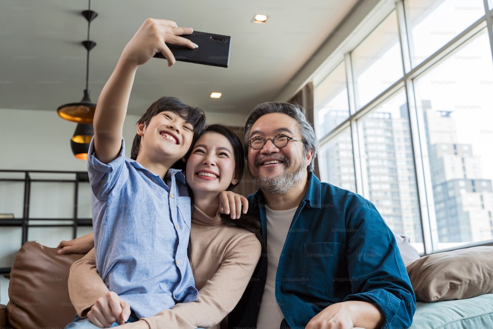 카메라를 향해 웃고 있는 가족. 셀카를 찍는 행복한 가족, 집에서 전화로 웃고 있다