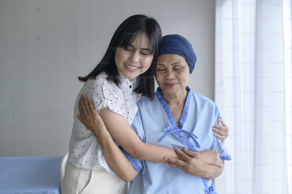 Mujer paciente de cáncer que usa pañuelo en la cabeza y su hija de apoyo en el concepto de hospital, salud y seguro.