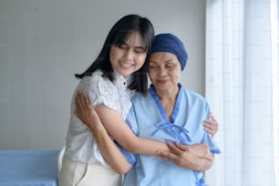 Mujer paciente de cáncer que usa pañuelo en la cabeza y su hija de apoyo en el concepto de hospital, salud y seguro.