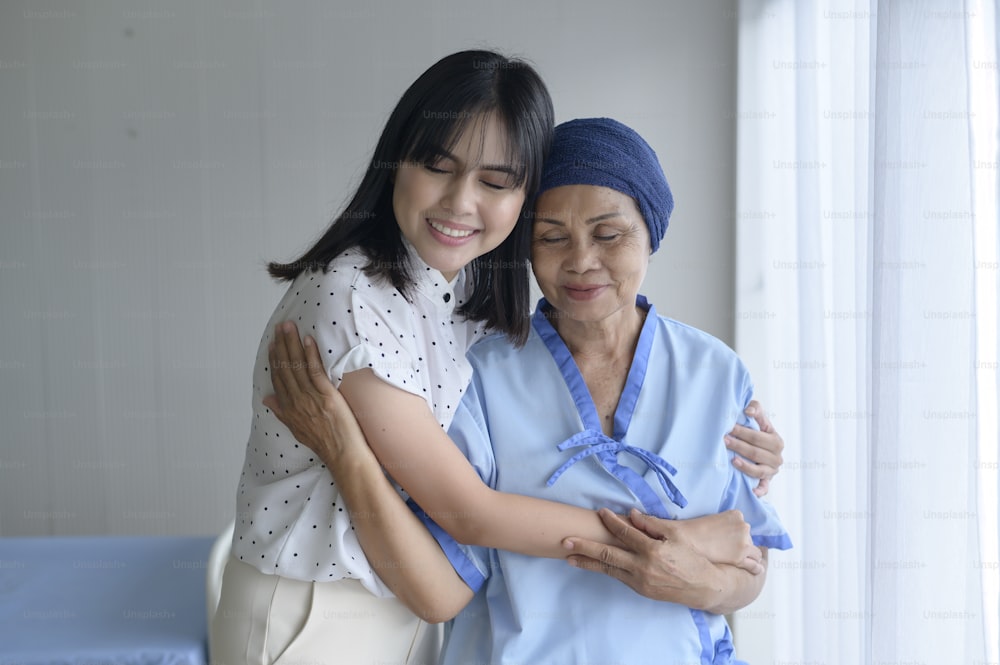 Cancer patient woman wearing head scarf and her supportive daughter in hospital, health and insurance concept.